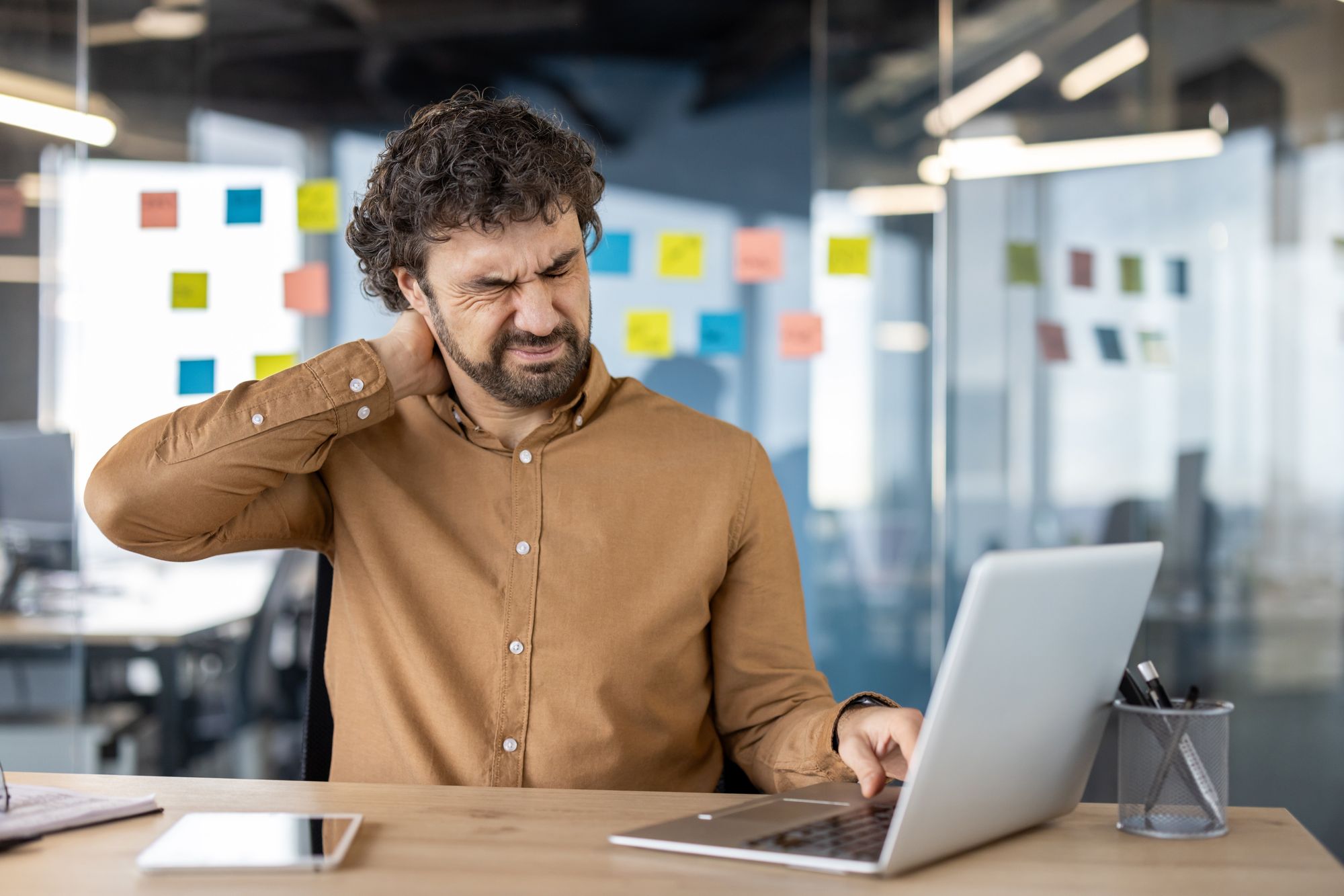 Office_worker_with_neck_tension_trying_to_relieve_neck_and_shoulder_pain_from_desk_work