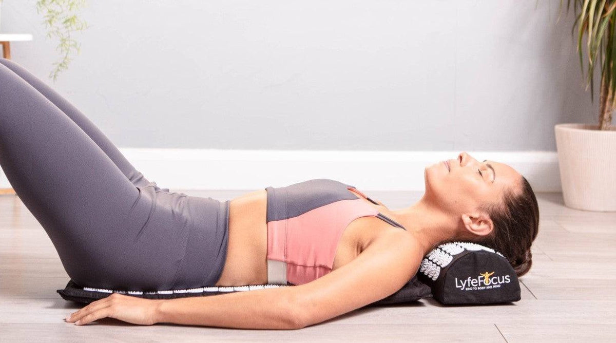 Woman relaxing on a LyfeFocus acupressure mat and neck pillow at home